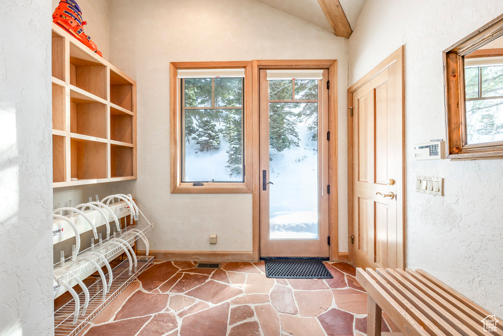Entryway with healthy amount of natural light, stone flooring, and lofted ceiling