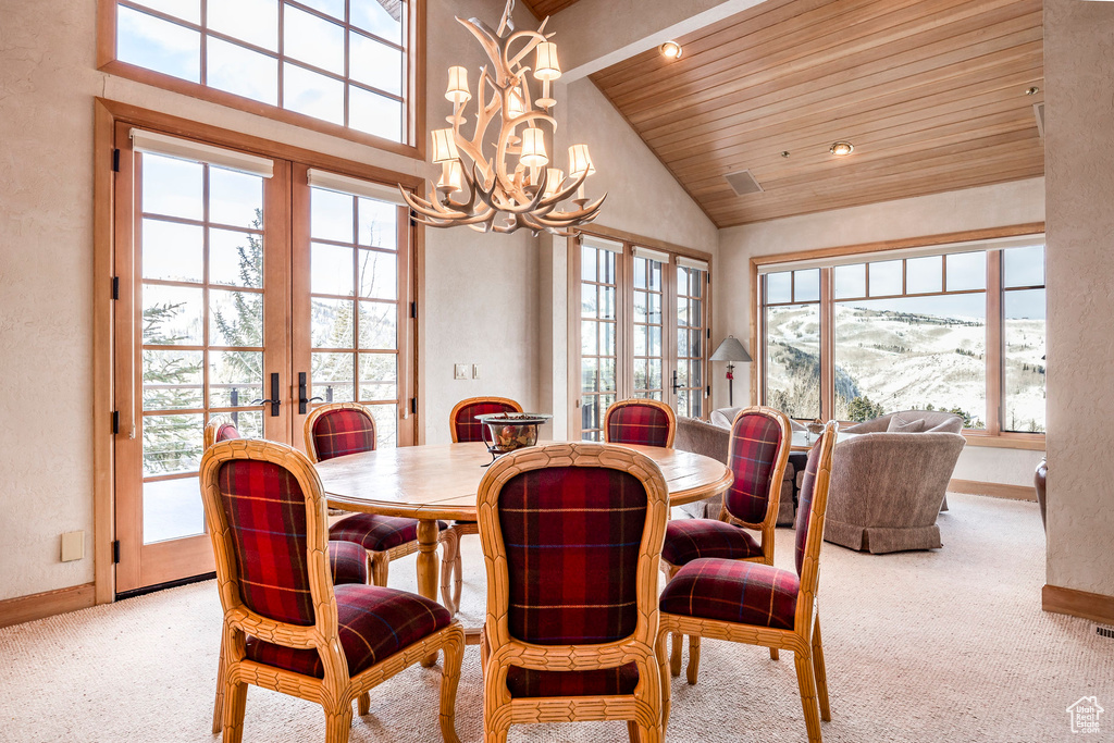 Carpeted dining area with french doors, wood ceiling, a chandelier, and high vaulted ceiling