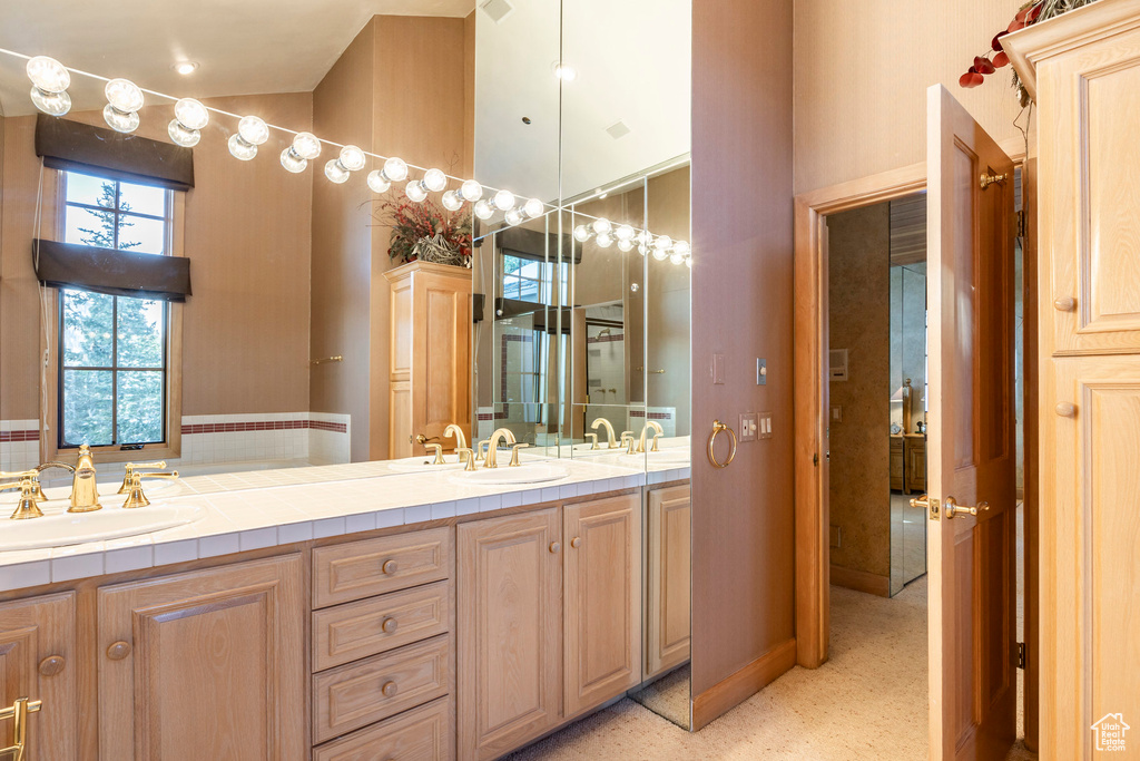 Full bath featuring double vanity and a high ceiling