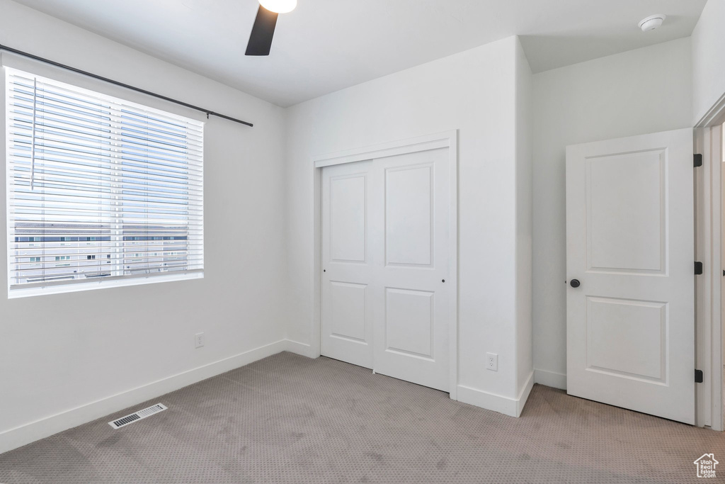 Unfurnished bedroom with light carpet, a closet, and ceiling fan