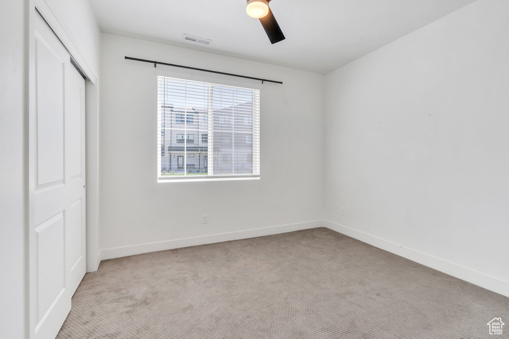 Unfurnished bedroom featuring light carpet, a closet, and ceiling fan