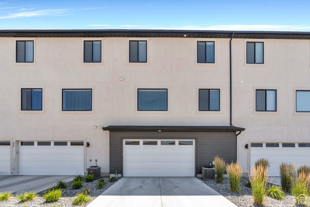 View of property featuring stucco siding, a garage, and concrete driveway