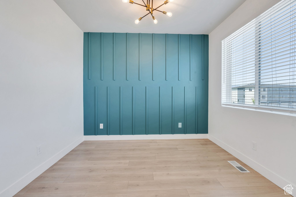 Unfurnished room featuring a chandelier and wood finished floors