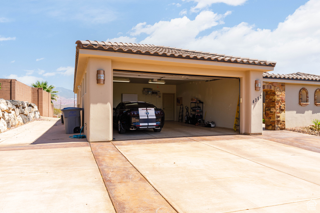 View of front of house with concrete driveway, stucco siding, a tile roof, and an attached garage