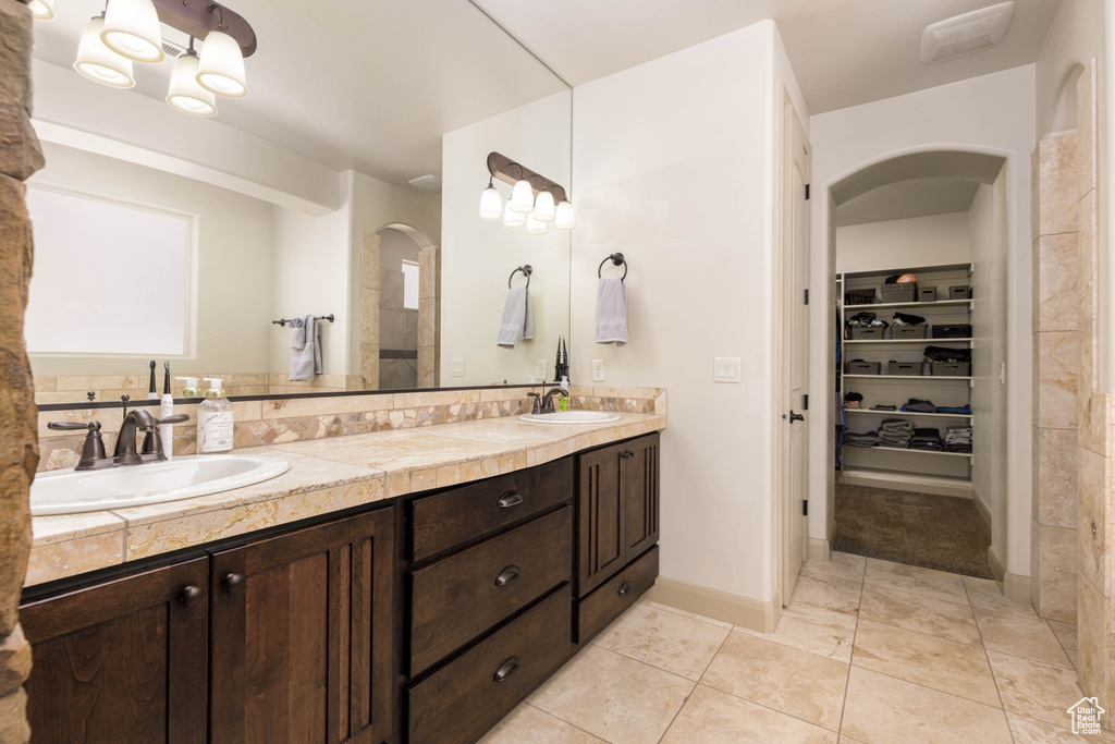 Full bathroom featuring double vanity, a spacious closet, and tile patterned flooring