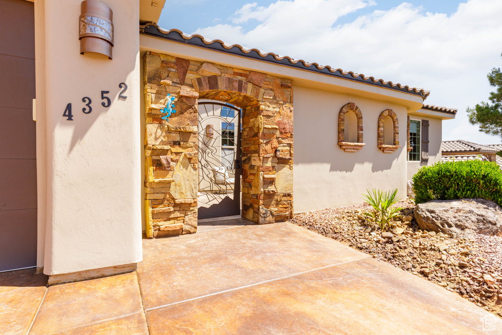 View of exterior entry with stone siding, stucco siding, and a tile roof