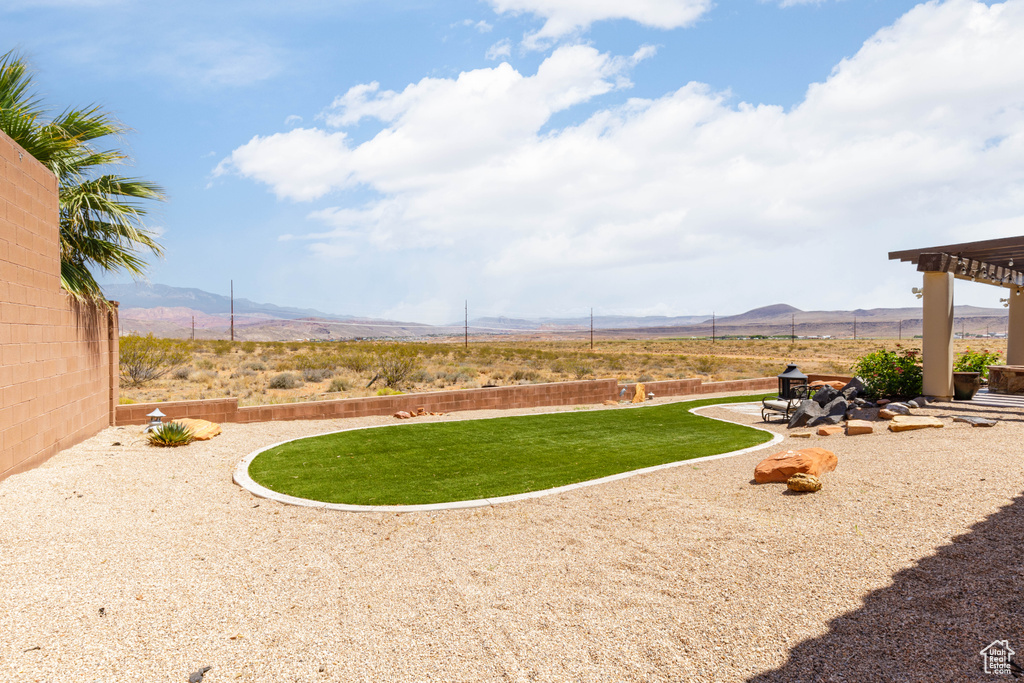 View of green lawn featuring a mountain view and a patio