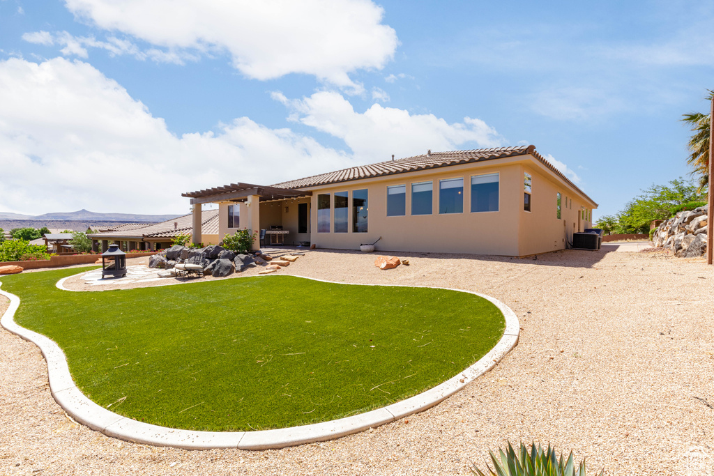 Back of property featuring a pergola, a patio, a tile roof, stucco siding, and a yard