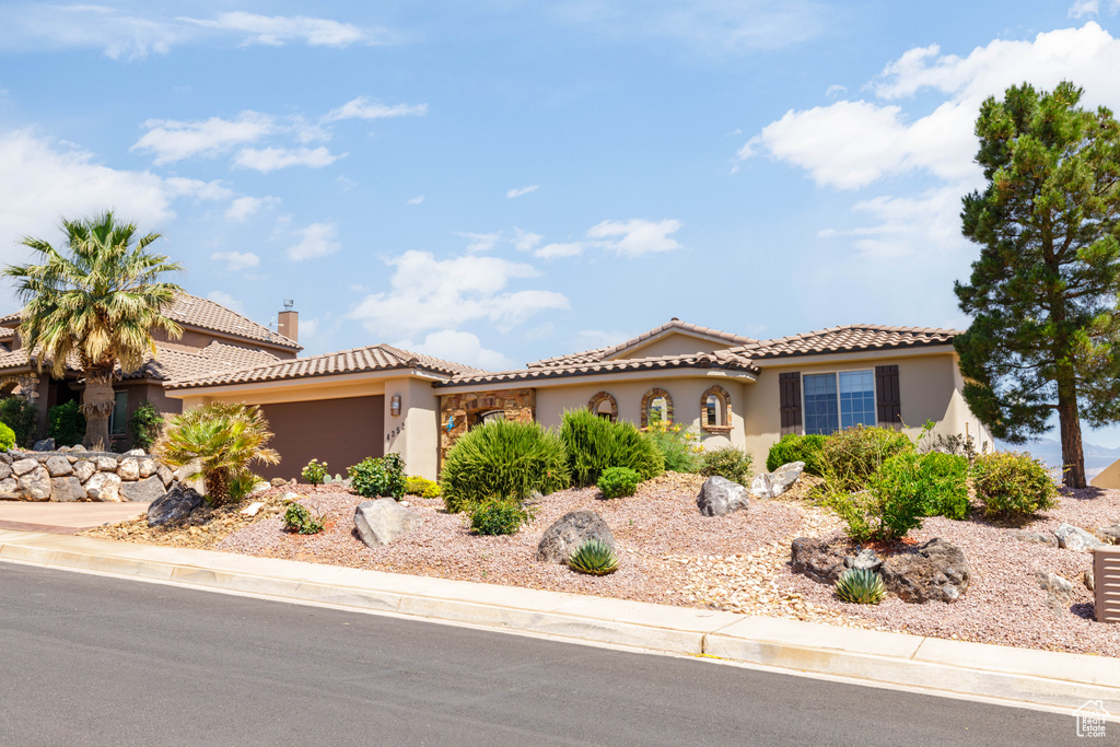 Mediterranean / spanish-style house featuring stucco siding, an attached garage, a tile roof, and driveway