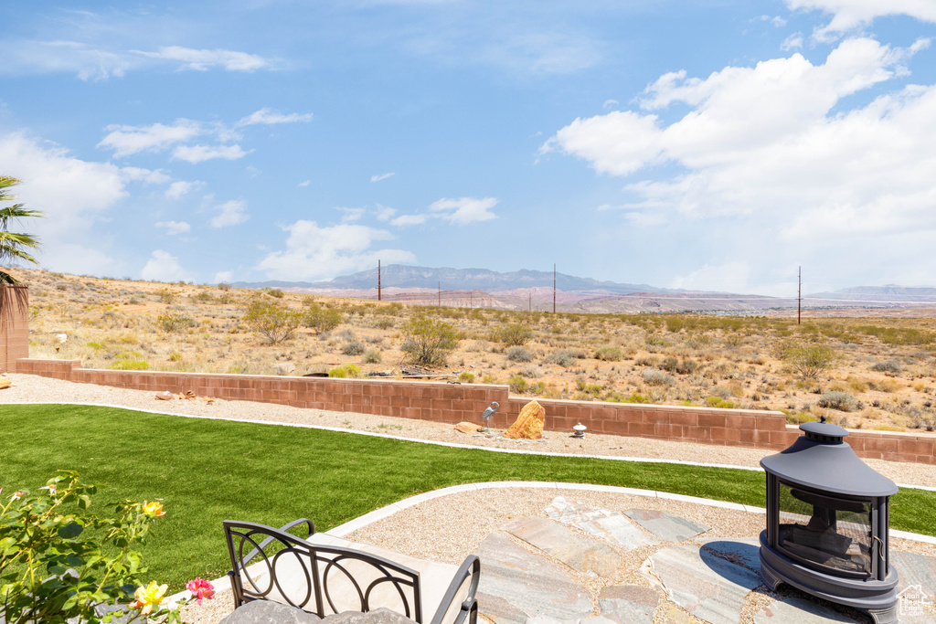 View of grassy yard featuring a mountain view and a patio