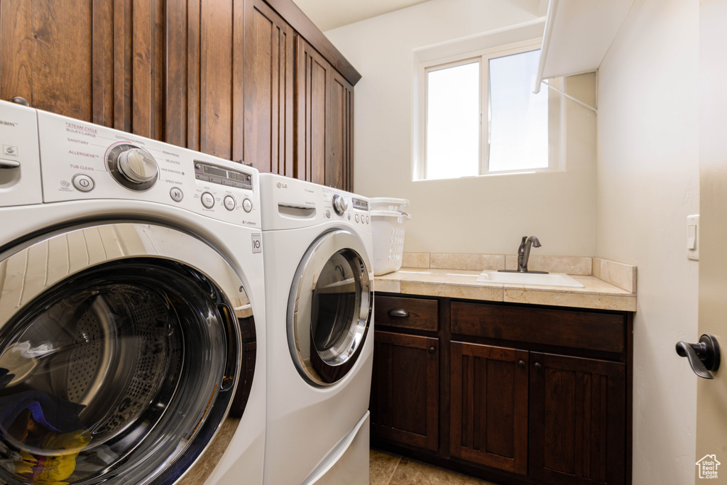 Washroom featuring independent washer and dryer, cabinet space, and light tile patterned floors
