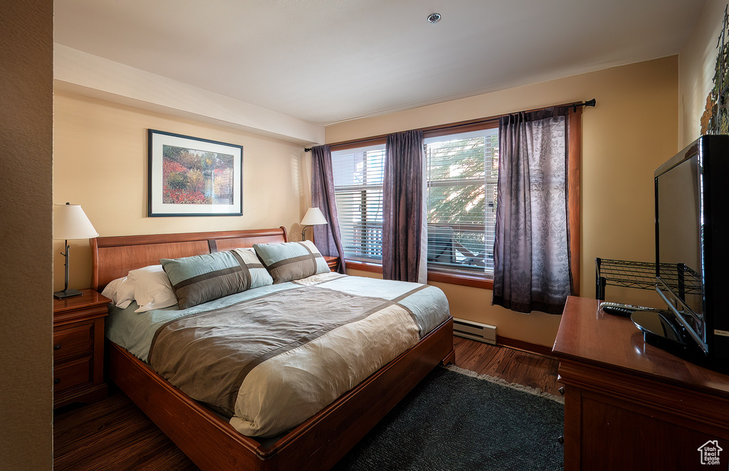 Bedroom featuring a baseboard heating unit and wood finished floors