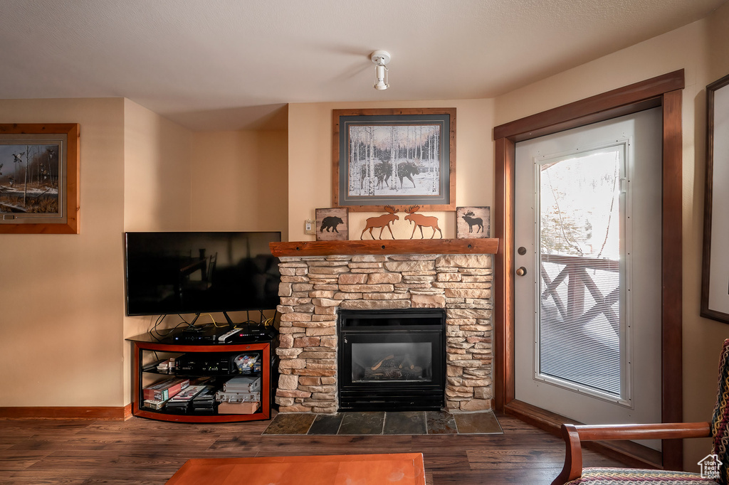 Living room with wood finished floors and a stone fireplace