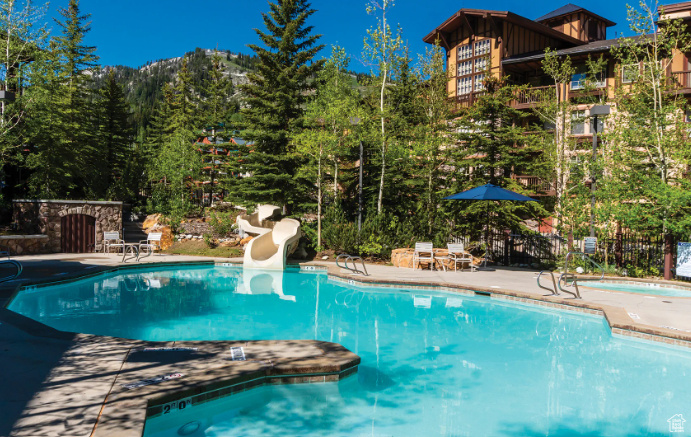 Community pool with a water slide and a patio area