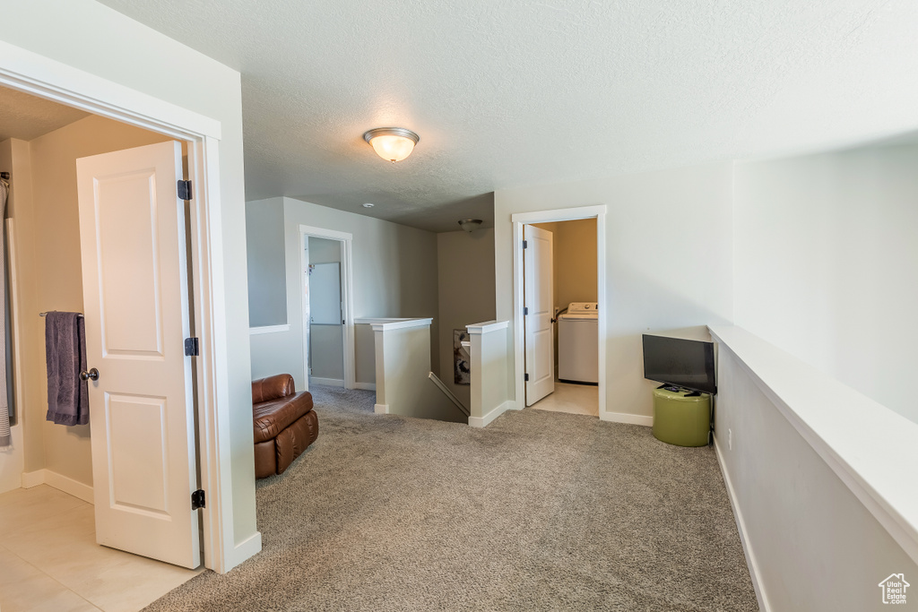 Empty room featuring a textured ceiling, washer / dryer, and light carpet