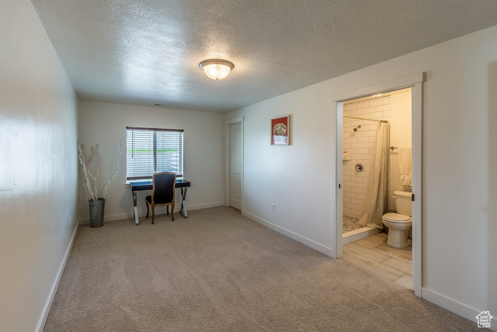 Home office featuring a textured ceiling and light carpet