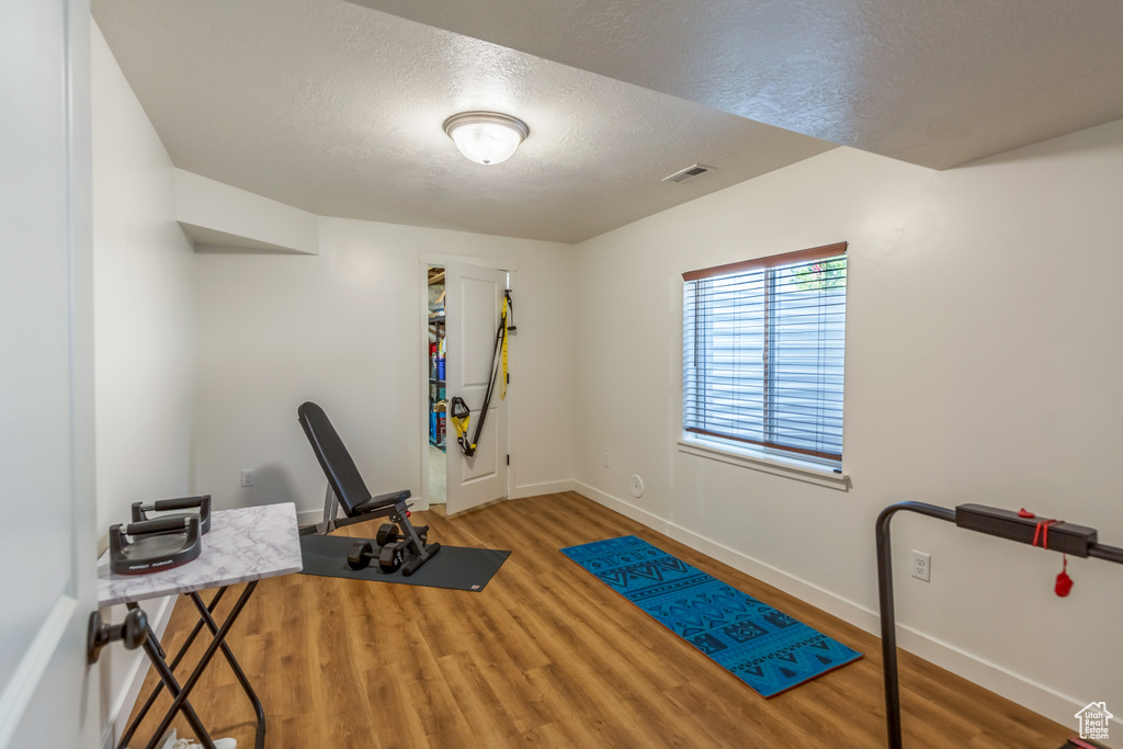 Exercise room with wood finished floors and a textured ceiling