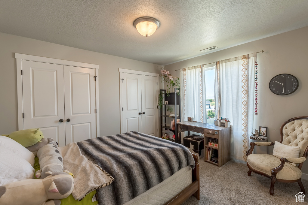 Carpeted bedroom featuring two closets and a textured ceiling