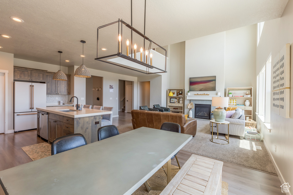 Dining area featuring dark wood-style floors, recessed lighting, a glass covered fireplace, and a high ceiling