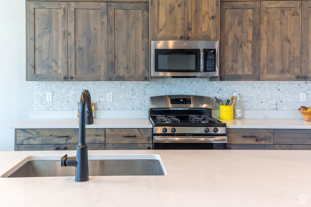 Kitchen with stainless steel appliances, tasteful backsplash, and dark brown cabinetry