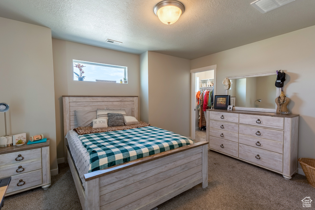 Carpeted bedroom featuring a spacious closet and a textured ceiling