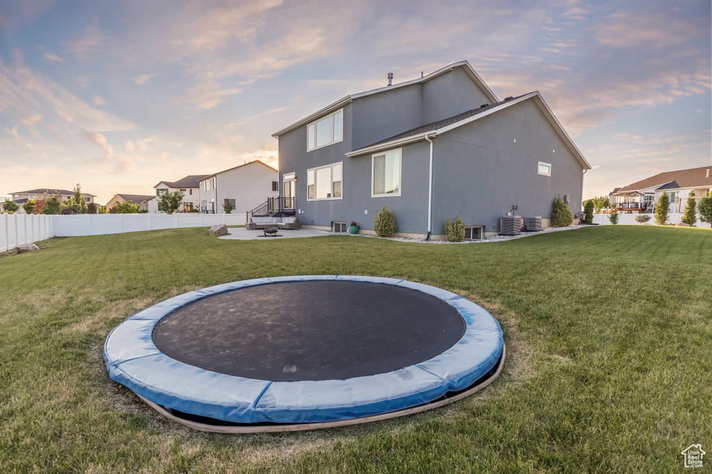 Rear view of property featuring a trampoline and stucco siding