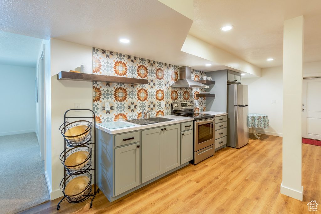 Kitchen featuring open shelves, stainless steel appliances, wall chimney range hood, gray cabinetry, and recessed lighting