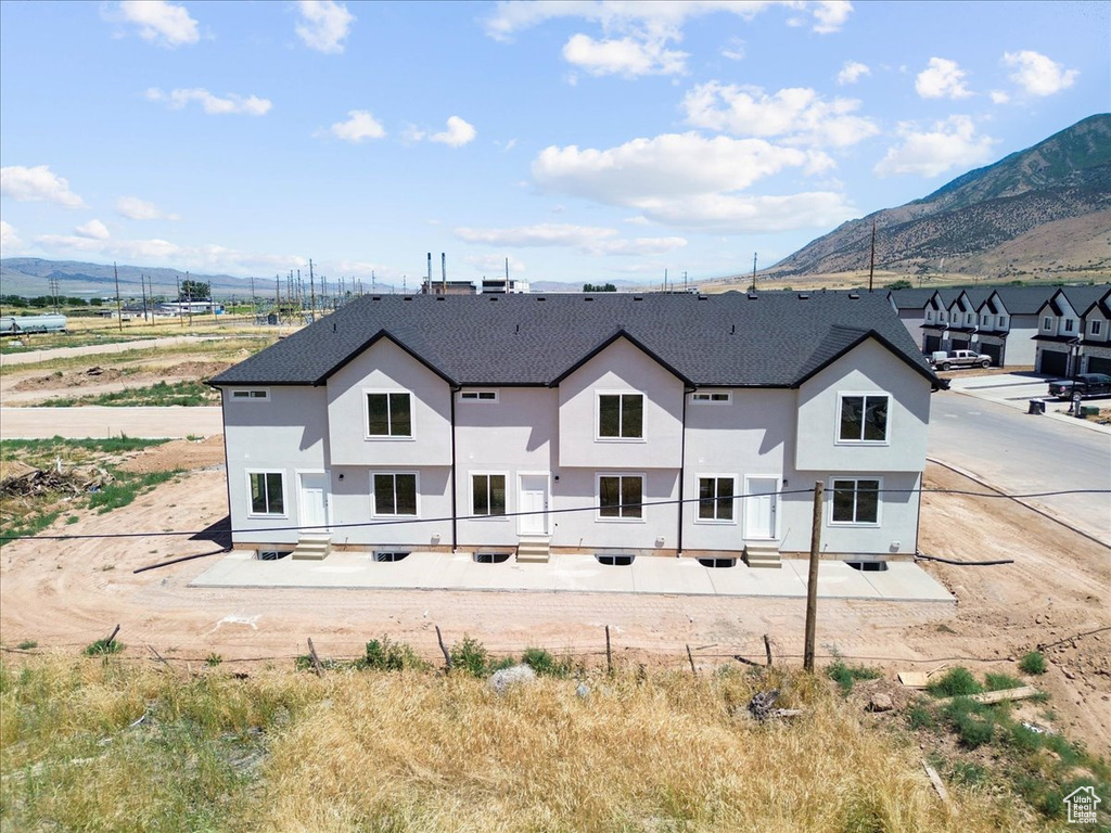 Rear view of property with a mountain view, a shingled roof, and stucco siding