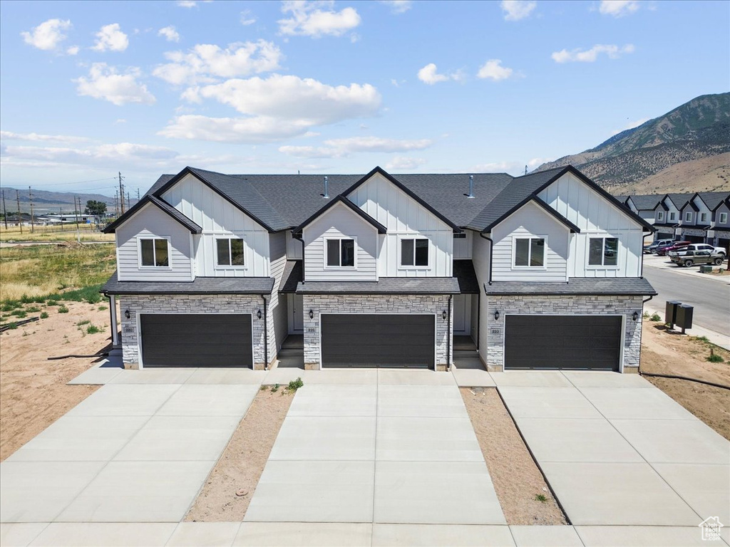 Modern farmhouse style home with board and batten siding, a garage, a mountain view, and concrete driveway