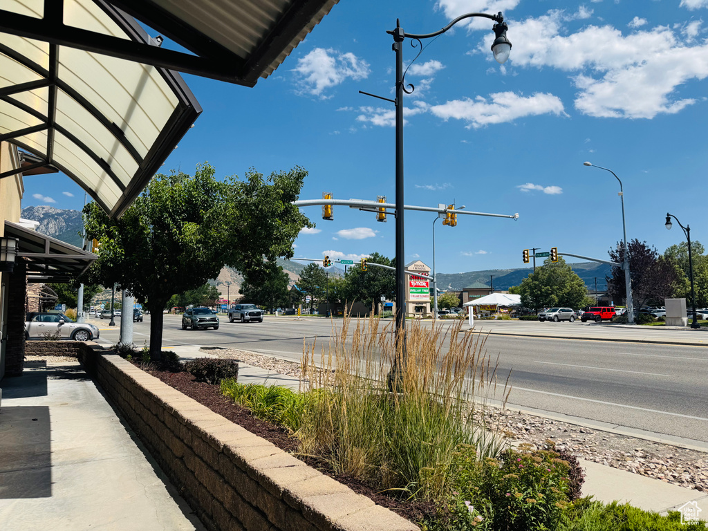 View of asphalt street featuring traffic lights, sidewalks, and street lights