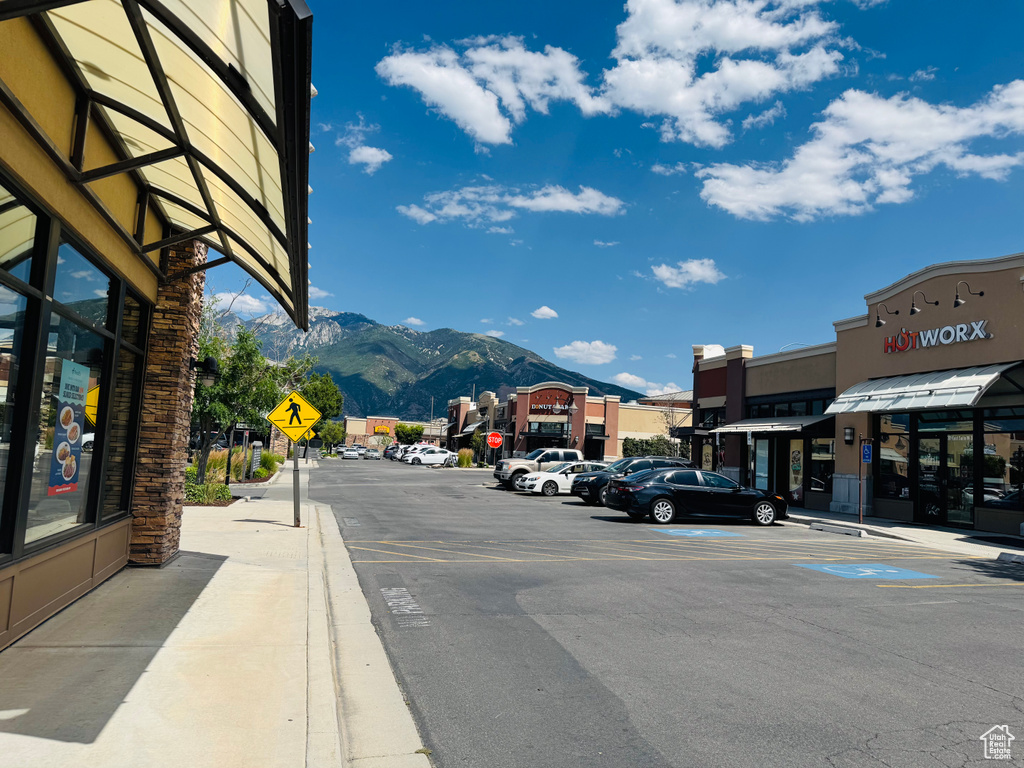 View of asphalt road featuring traffic signs, a mountain view, sidewalks, and curbs