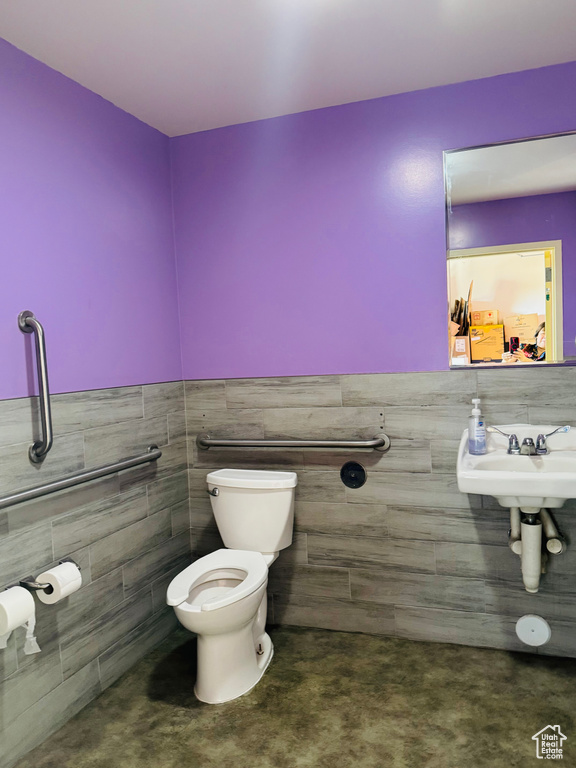 Half bath featuring tile walls and a wainscoted wall