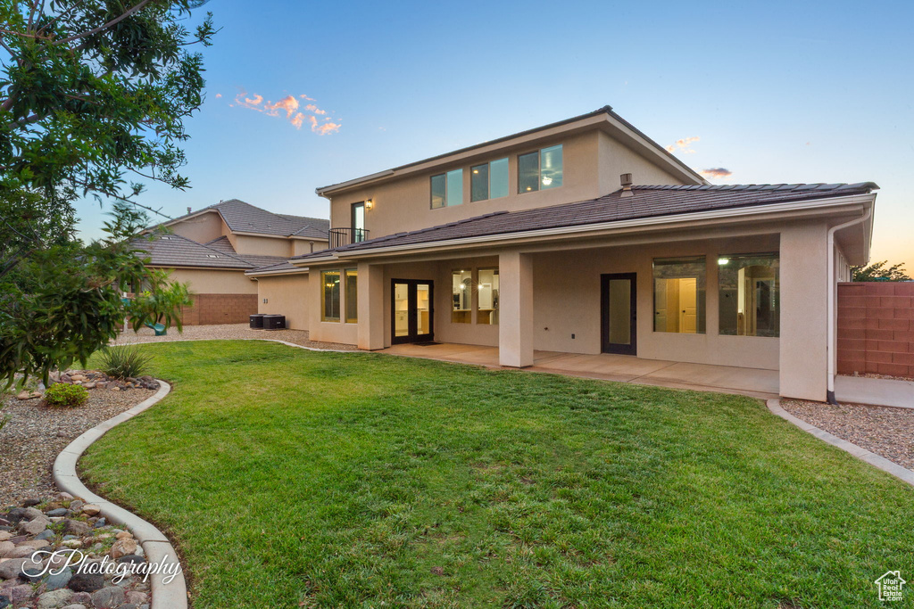 Back of house with stucco siding, french doors, a patio area, and a tiled roof
