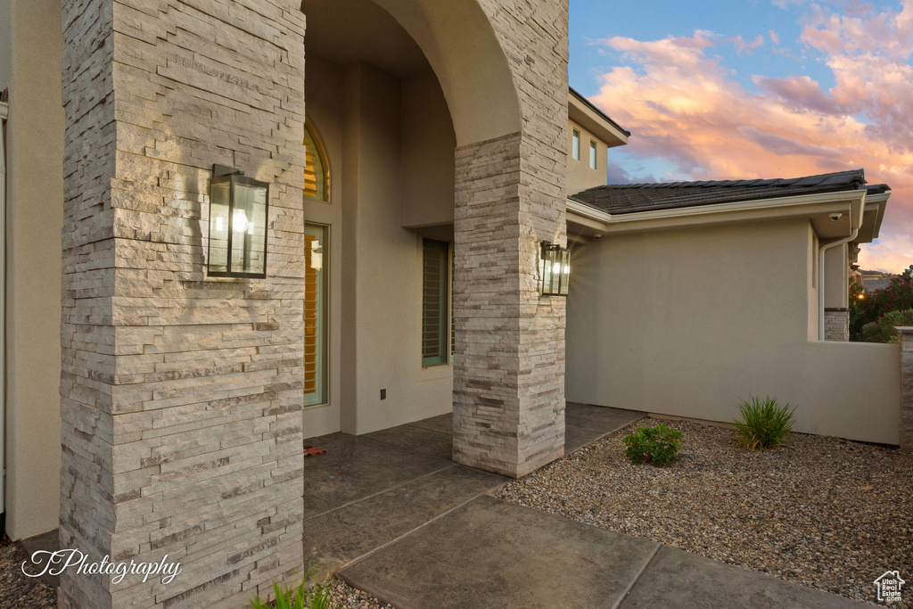 View of exterior entry featuring stucco siding and a patio area