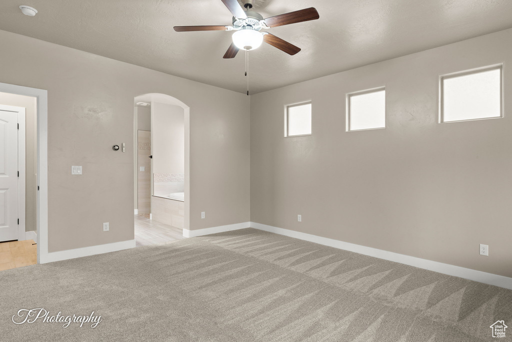 Spare room with arched walkways, light carpet, ceiling fan, and a smoke detector