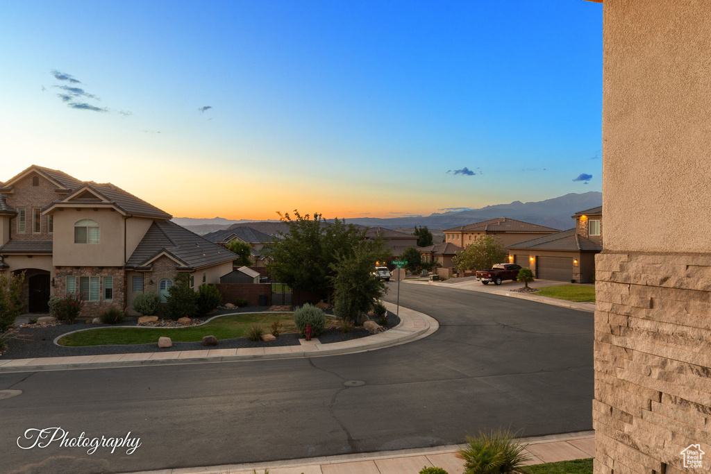 View of asphalt road featuring sidewalks, curbs, a mountain view, a residential view, and traffic signs
