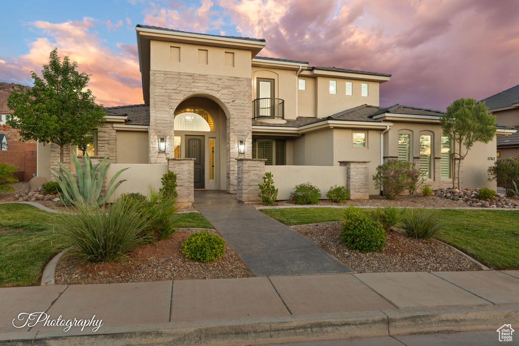 View of front of property featuring stone siding, stucco siding, and a fenced front yard