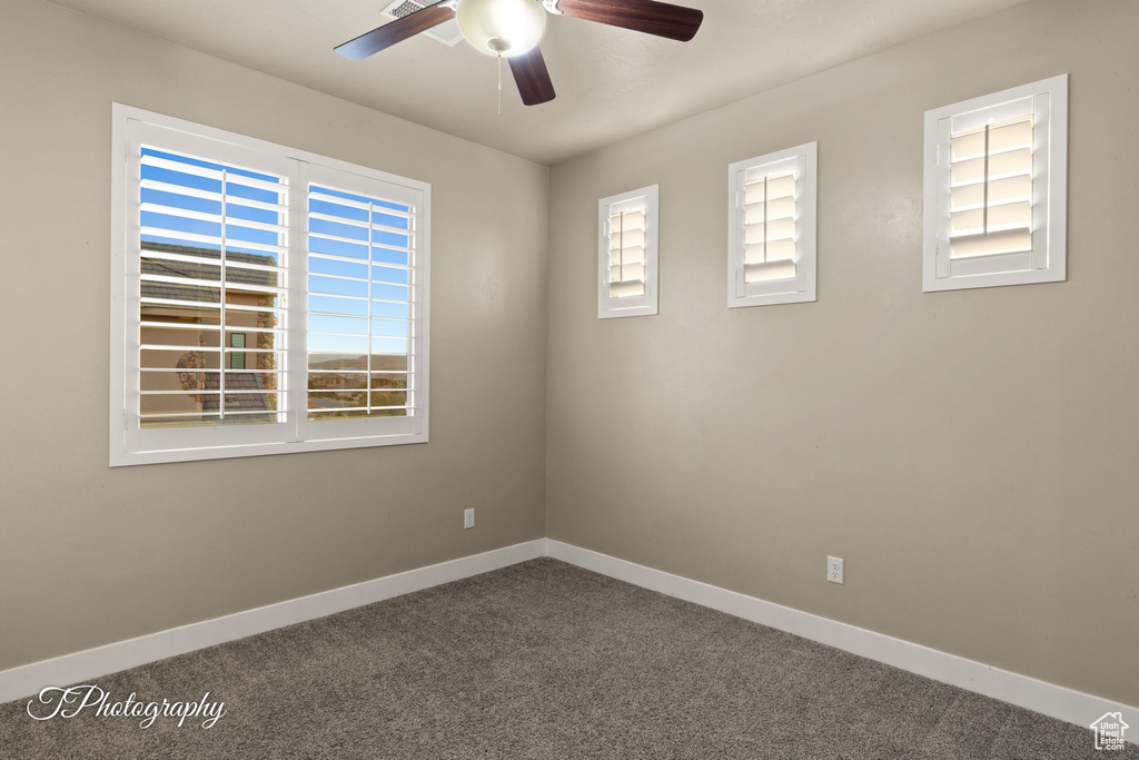 Carpeted empty room featuring a ceiling fan and baseboards
