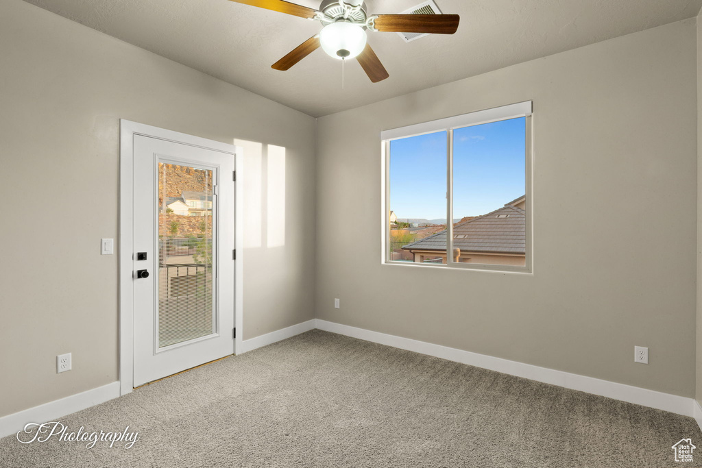 Carpeted spare room featuring plenty of natural light and a ceiling fan