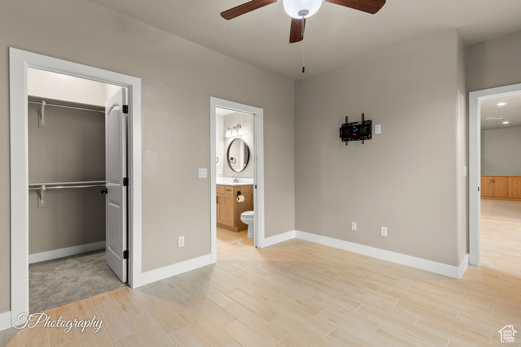 Unfurnished bedroom with light wood finished floors, a spacious closet, connected bathroom, and a closet