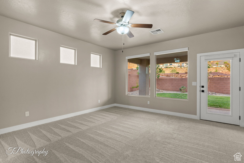 Spare room featuring a ceiling fan and light carpet
