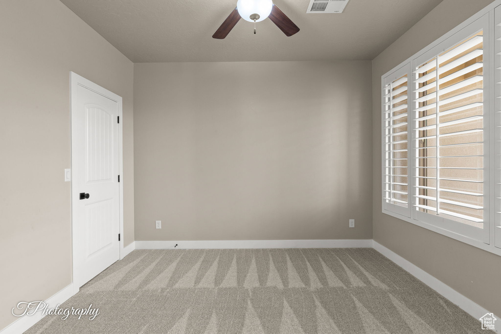 Carpeted empty room featuring a ceiling fan and baseboards