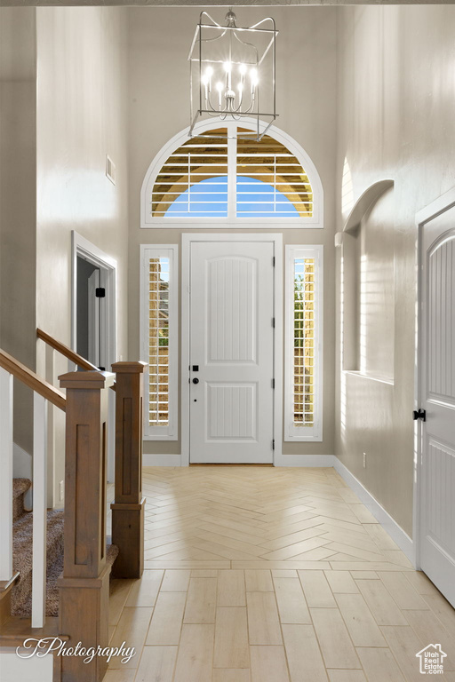Foyer featuring a high ceiling, a chandelier, stairs, and plenty of natural light
