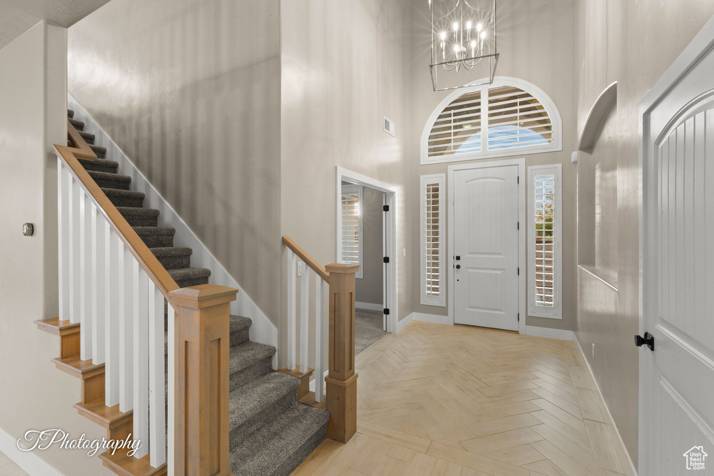 Foyer entrance with stairs, a chandelier, and a high ceiling