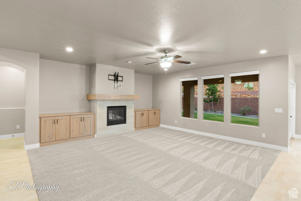 Unfurnished living room featuring ceiling fan, arched walkways, a fireplace, and recessed lighting