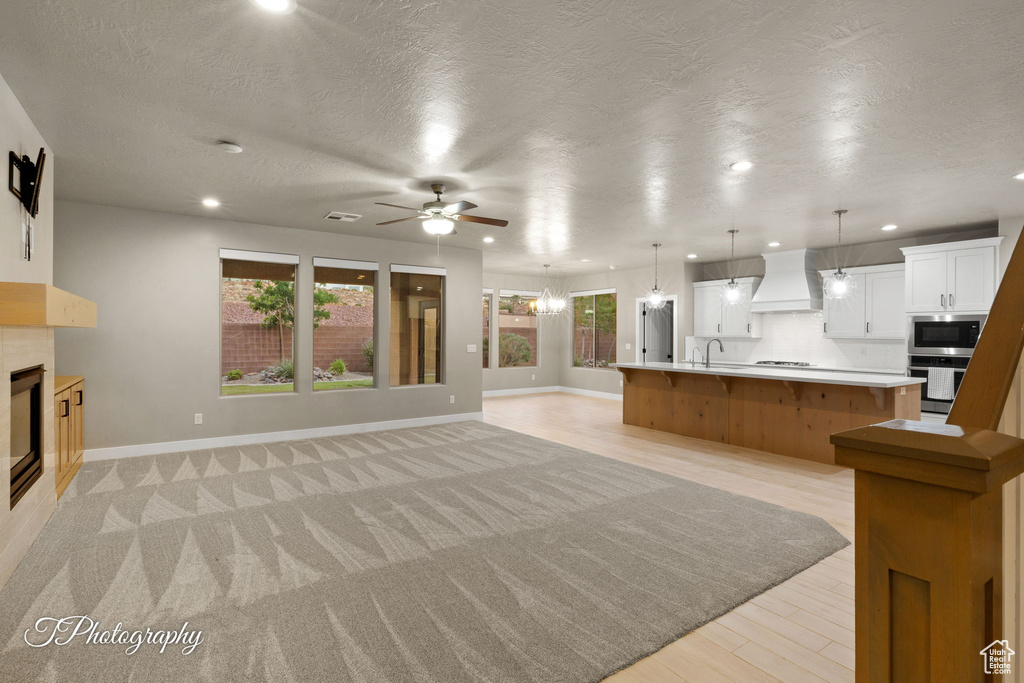 Unfurnished living room with a tiled fireplace, ceiling fan, recessed lighting, and a textured ceiling