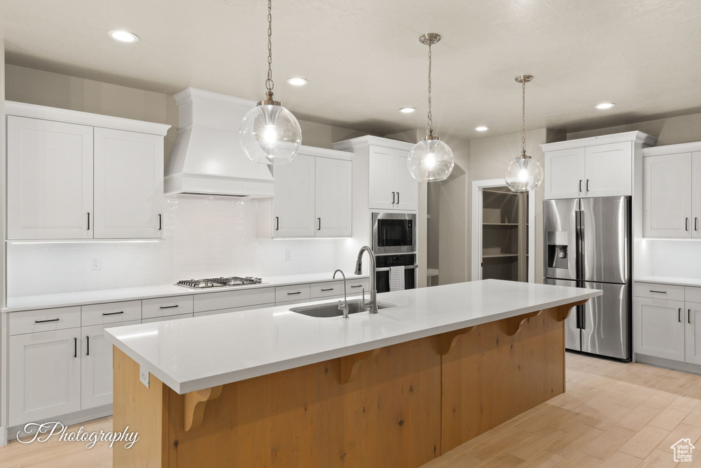 Kitchen with stainless steel appliances, premium range hood, light countertops, a kitchen bar, and recessed lighting