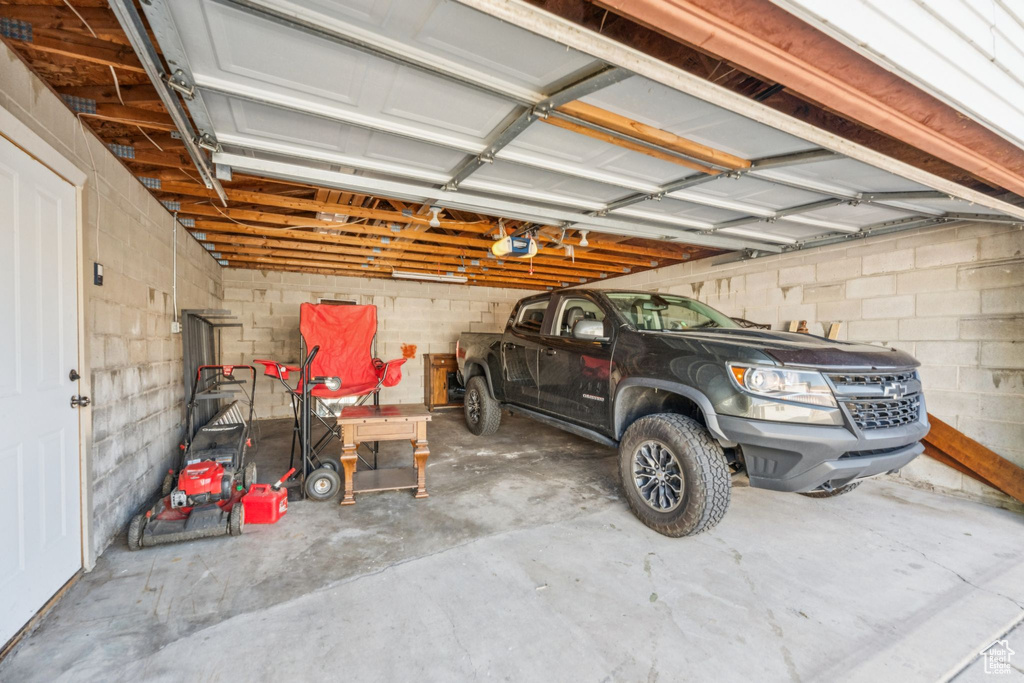 Garage featuring a garage door opener and concrete block wall
