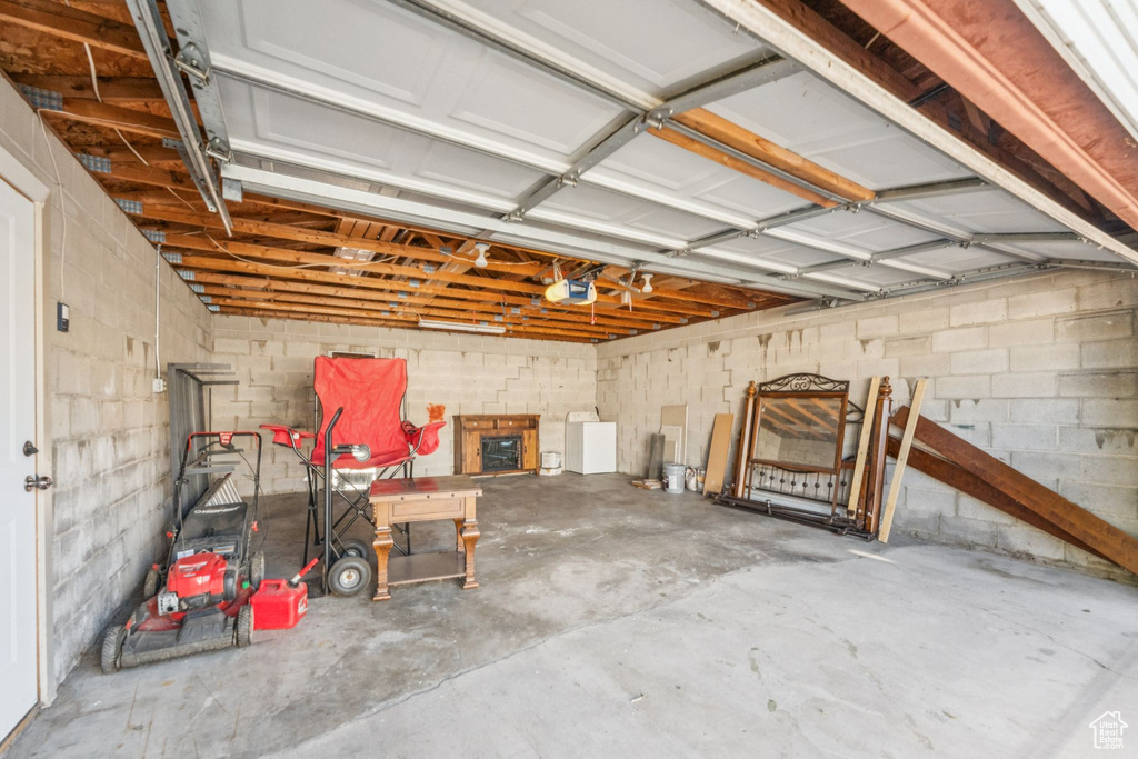 Garage featuring a garage door opener and concrete block wall