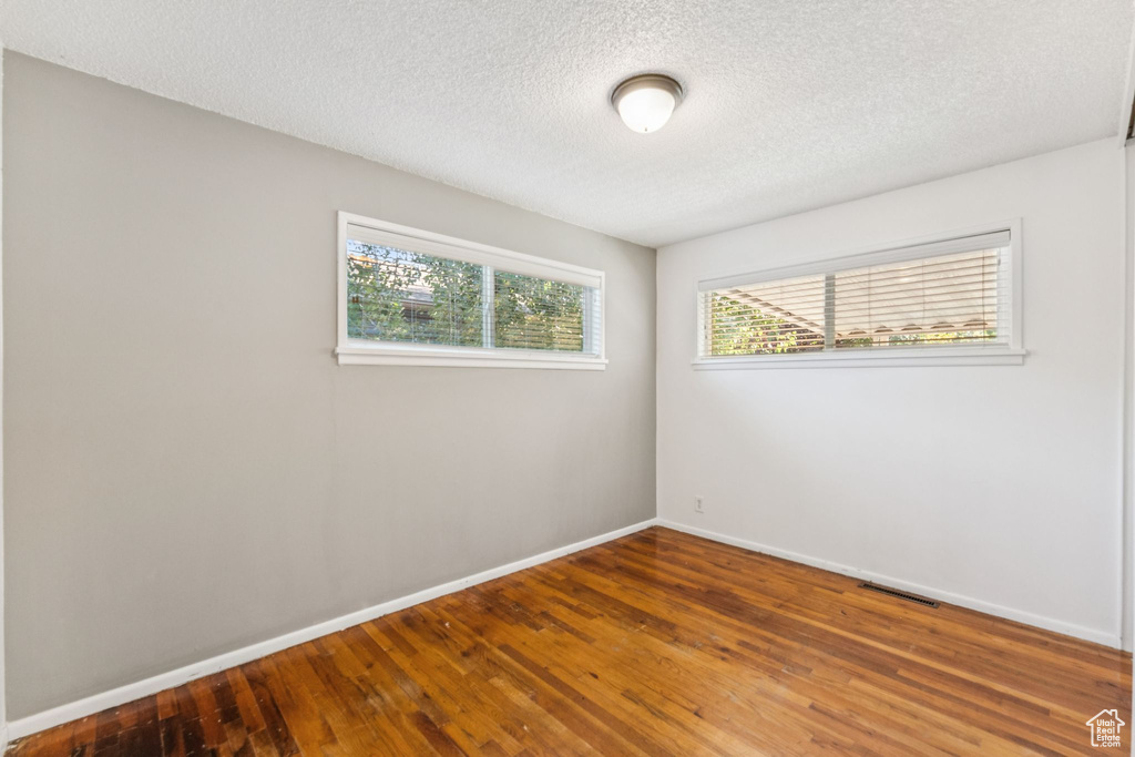 Spare room featuring a textured ceiling and wood finished floors